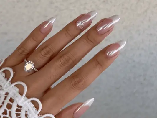 A chrome French manicure with two hearts on the ring finger