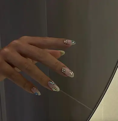 Nude manicure with bejeweled nail stickers in flower shapes