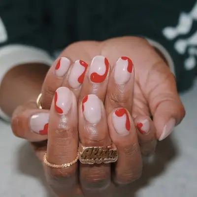 Hands with nails painted in a design featuring red swirl patterns