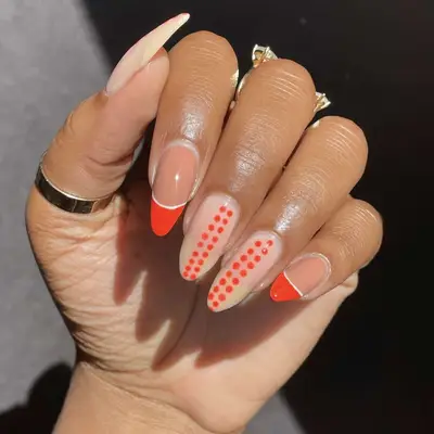 Hand with nails featuring decorative red and clear designs