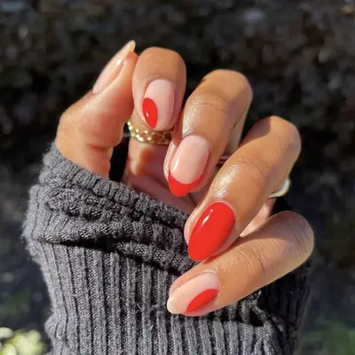 Close-up of a hand with red and natural painted nails