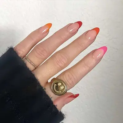 A hand shown with gradient-colored styled nails and a ring featuring a happy face design
