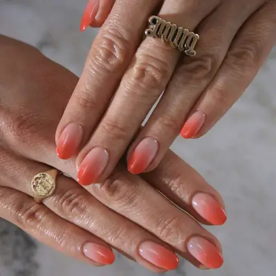 Close-up of hands with ombré nail art and decorative rings, showcasing the manicure details