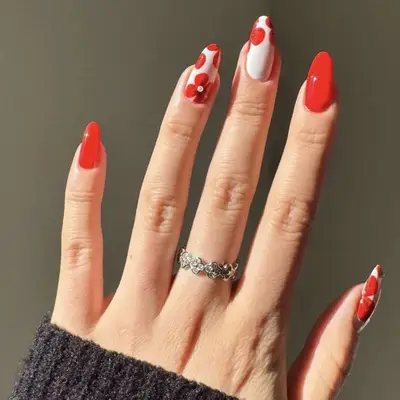 Hand with red and white decorated manicure wearing a silver ring