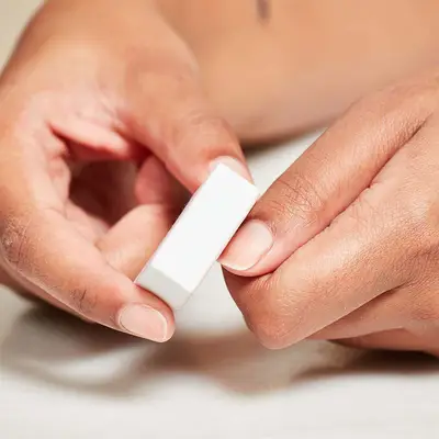 Close up of a woman using one hand to buff the thumb nail of the other.