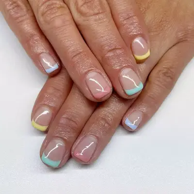 sheer nude short nails with baby yellow, pink, and teal french tips