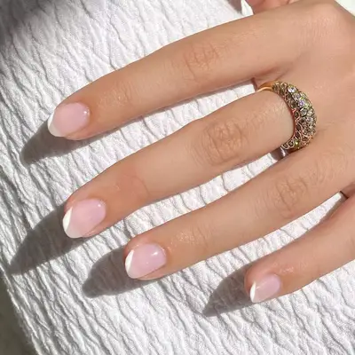 sheer nude short nails with asymmetric white french tips