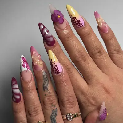 A person displays detailed artistic nail designs with floral patterns and various artistic decorations