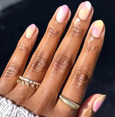 A hand with manicured nails and gold rings on fingers