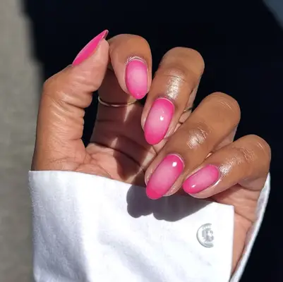 A hand displaying brightly colored manicure, featuring nail designs with a gradient effect, and wearing a white sleeve