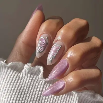 Hand with decorated fingernails, including a butterfly design on the ring finger