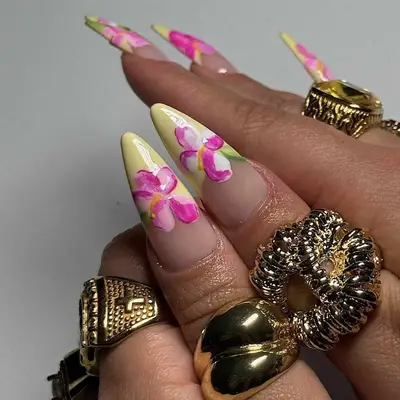 Hand with floral-painted nails and various gold rings