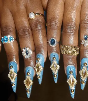 Close up of a set of nails, heavy in gold, gemstones, and tiny baroque portraits