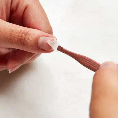 Woman applies the corner of a tea bag to the tip of her nail