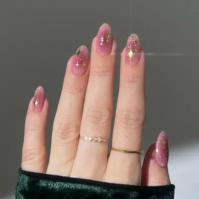 a pink aura manicure with glittery gold stars