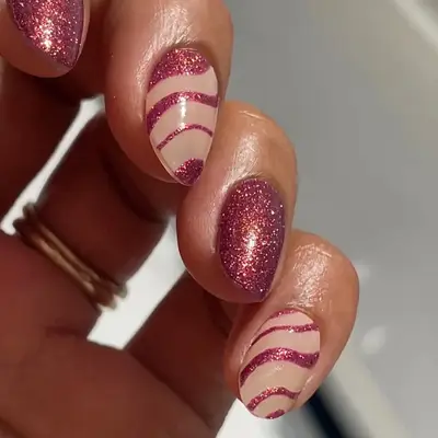 a glittery pink manicure with solid and striped nails