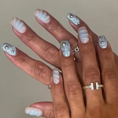 model with icy blue nails with silver chrome ball accents and 3D waves
