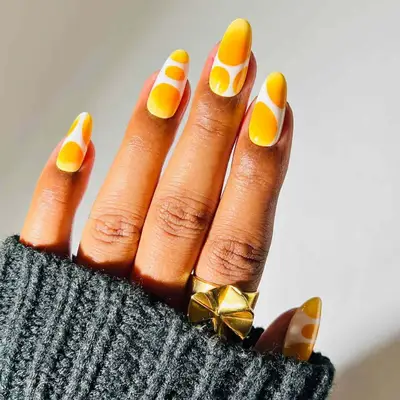 model with white nails featuring ombre yellow and orange dot design