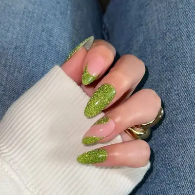 Sparkly green manicure with two accent negative-space nails.