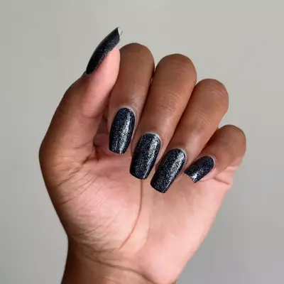 Black manicure with silver sparkles.