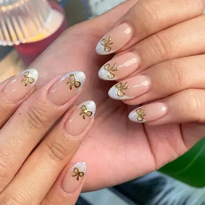 a short snowy french manicure with gold bows