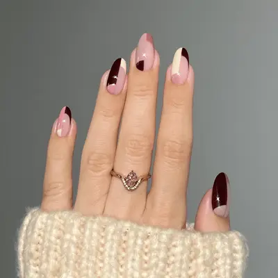 Close up of a mauve, cream, and burgundy manicure in a block print nail design.