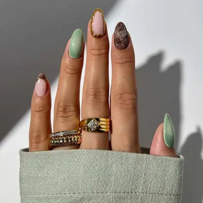 Manicure with green and brown tones, marble and aura designs, and gold border accent nail