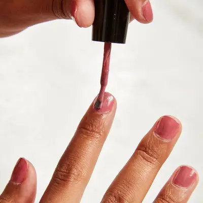 Woman adds nail polish to her chipped nail polish
