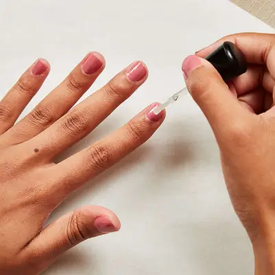 Woman adds topcoat to her freshly re-painted nail