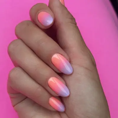 a hand with a pink, orange, and lavender ombre manicure