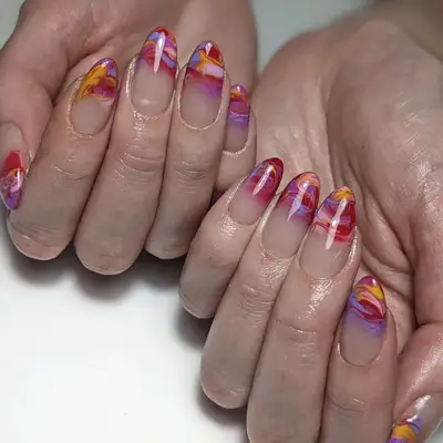 two hands with a red, purple, blue, pink, and yellow sunset marbled manicure