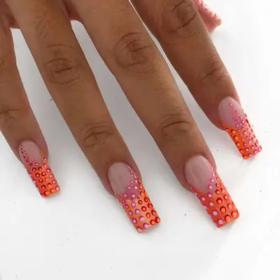 a hand with pink, orange, and red polka dot sunset manicure