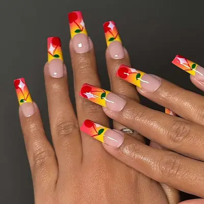 two hands with a yellow and red sunset french manicure with cherry nail art