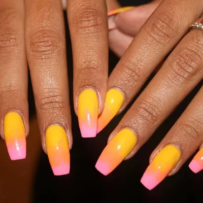 two hands with a yellow, orange, and pink sunset manicure