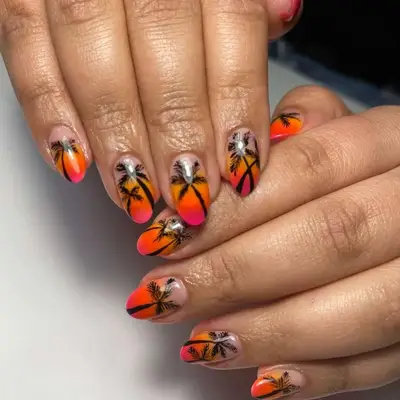 two hands with a red, orange, and pink with black palm trees manicure