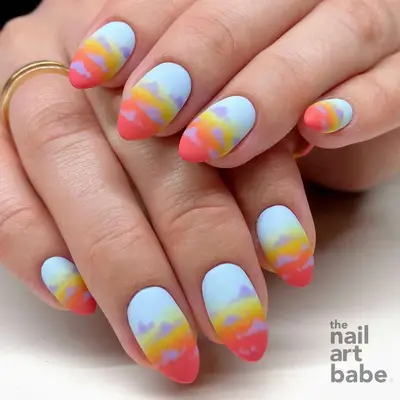 two hands with a blue, yellow, and orange sunset manicure with a matte finish