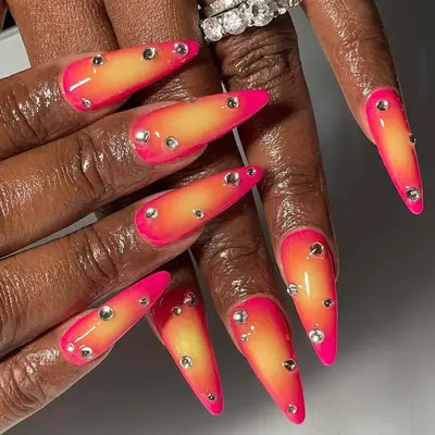 two hands with a pink and yellow sunset with rhinestones manicure