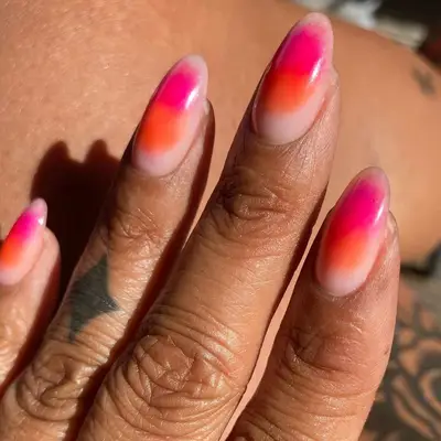 a hand with a pink and orange sunset manicure