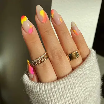 a hand with a nude base coat and pink, yellow, red, and orange sunset manicure