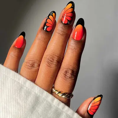 Hand with butterfly-themed nail art, wearing rings