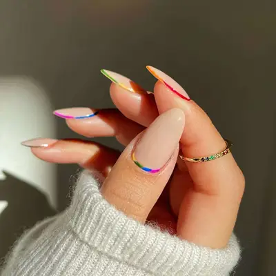 A neutral manicure with rainbow borders on each nail