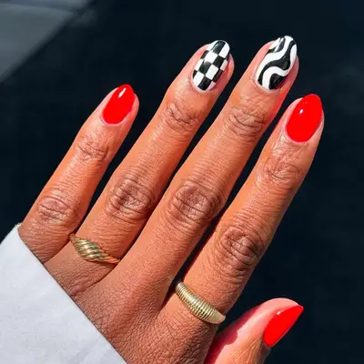 A manicure with red, black and white checker, and black and white swirl nails