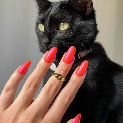 A reddish-orange manicure topped with a chrome coat