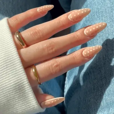 Long, almond-shaped nude nails with tiny white dots