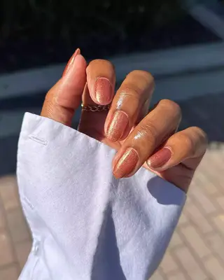 A hand with rose gold shimmer nails