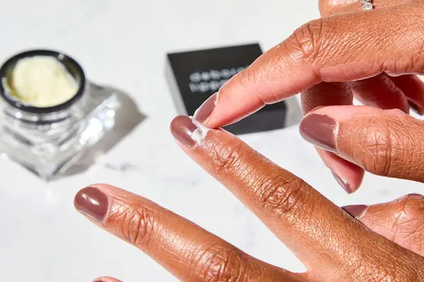 A person applying Deborah Lippmann The Cure Cuticle Repair Cream to their nail bed