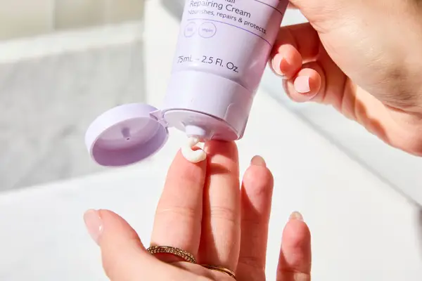 A person squeezing Caudalie Vinotherapist Hand and Nail Cream onto their finger tip