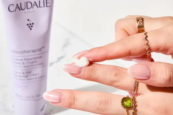 A person applying Caudalie Vinotherapist Hand and Nail Cream to their nail bed