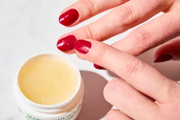 A person applying Mario Badescu Cuticle Cream to their nail bed