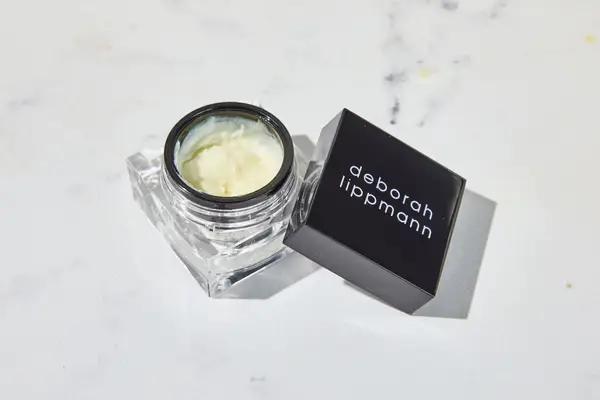 Deborah Lippmann The Cure Cuticle Repair Cream sitting on a marble countertop
